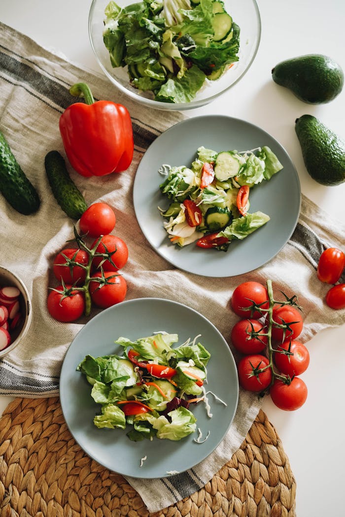 Salad on Gray Ceramic Plates Beside Vegetables on Table